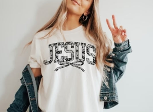 Person wearing a white t-shirt with 'JESUS' printed on it, making a peace sign.